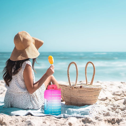 woman on he beach holding popsicle and buildLife 1 Gallon Water Bottle on the group next to her
